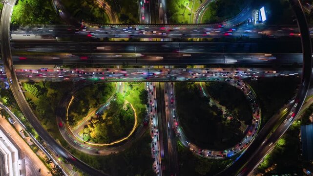 Aerial timelapse of Jakarta highway interchange at night. Bright traffic trails, glowing roads, and dynamic city infrastructure in Indonesia's capital.