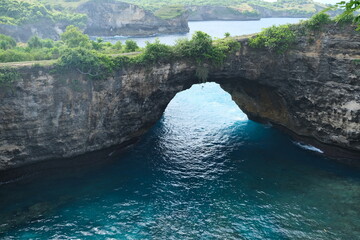 Scenic view of a large rock arch and turquoise bay at Broken Beach, a famous coastal landmark on...