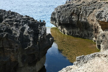 A stunning natural rock pool with clear water nestled between jagged cliffs at Angel's Billabong, a famous coastal spot in Nusa Penida, Bali.