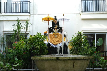 A traditional Balinese Hindu shrine adorned with ceremonial umbrellas and offerings, set above a...