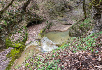 a riverbed with an exposed rocky bottom, a small stream and a current of water, the spring period...