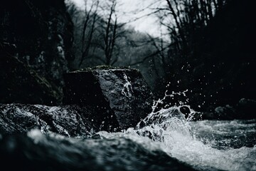 Dark, rocky stream splashing over stones in a forest