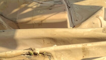 Abstract background of weathered and decaying beige plastic with cracks and folds.