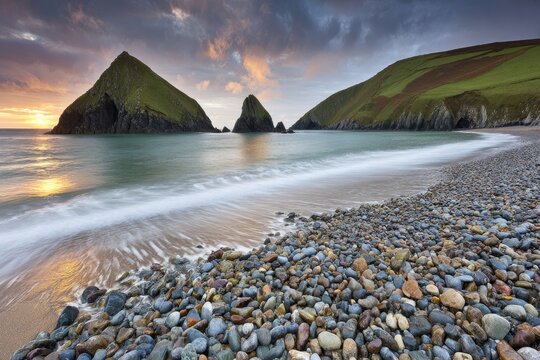 Coastal scene at sunrise with dramatic rock formations and a pebble beach
