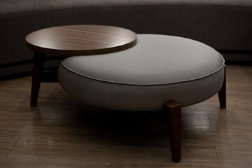 Modern round grey leather ottoman with a built-in dark wood coffee table. Elegant, minimalist...