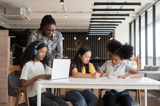 Female teacher teaching student using laptop computer in classroom. Student e-learning on laptop computer. Teacher assistance student using computer class in classroom