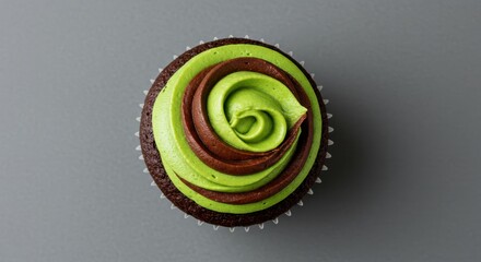 Chocolate cupcake with vibrant green and brown swirl frosting on a neutral gray background