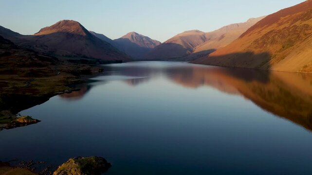 Over Wastwater lake and screes NE toward Wasdale Head, Great Gable and Scafell Pike. Lake District National Park, Cumbria, England. Spring sunset light. 4k video fly in over