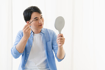 眉コーンシーラーを使う若い男性　ビューティイメージ