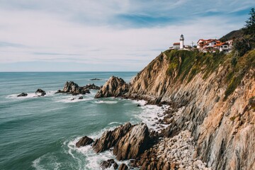 Coastal cliffs meet the sea, a lighthouse crowns the hill