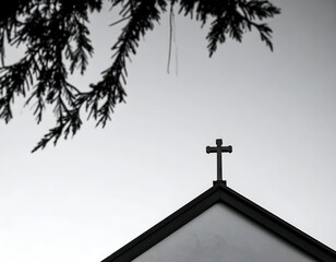 Minimalist black and white image of a church cross against a bright sky, framed by silhouetted branches.
