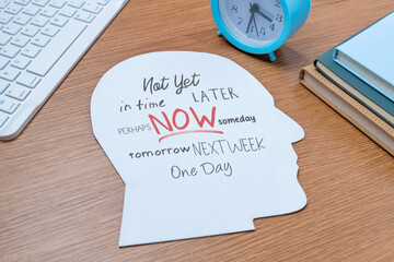 A paper cutout in the shape of a human head on a table with various words related to time and...