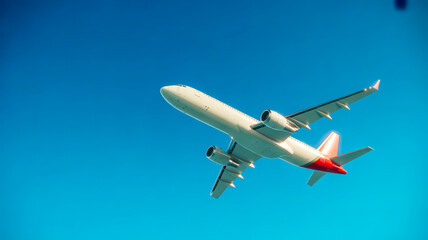 White passenger jetliner red tail blue sky airplane