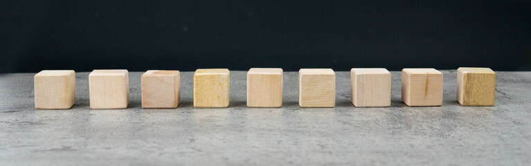 Nine blank wooden blocks in a row on table with blank space for your text, letters or numbers.