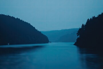 Misty, tranquil lake scene, dark silhouettes of mountains and trees