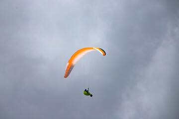 A man with a paraglider in front of a blue sky.