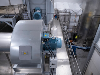 Blue electric motors and mechanical equipment on steel platform in manufacturing facility...