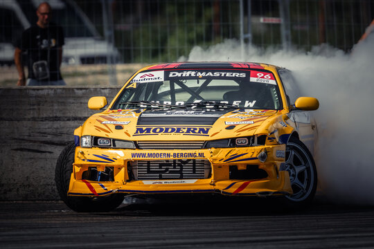 The image features a vibrant yellow racing car with sponsor logos, such as MODERN and DYKEMASTERS, in action on a racetrack The car is captured mid-drift, creating a dynamic scene of speed and control