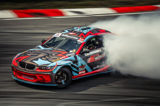 The image depicts a dynamic scene of a high-performance sports car in action on a racetrack, captured with motion blur to convey speed and power