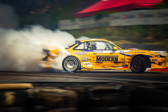 Speeding through the air, a vibrant yellow racing car emblazoned with 'MODERN' leaves a trail of smoke in its wake