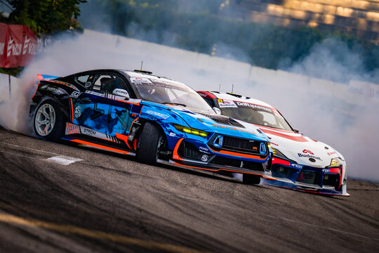 Two race cars are racing on a track, leaving behind a trail of smoke as they speed through the air