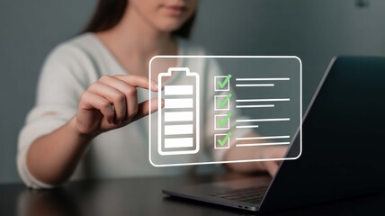 Woman's hand interacting with a digital checklist and battery icon on laptop screen, symbolizing progress and efficiency, achieving goals