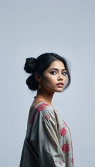 Fototapeta premium Portrait of beautiful asian woman with floral dress and hair bun looking over shoulder studio shot