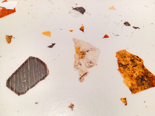 Close-up, abstract view of a light-colored terrazzo floor with scattered fragments of orange,...