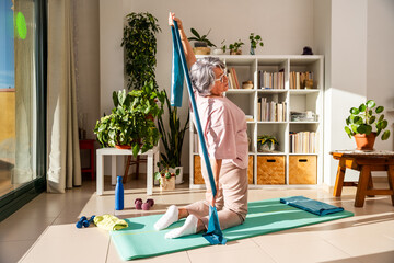 Old Lady Practices Stretching Exercises With Elastic Band at Home for Better Flexibility and Health