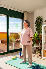 Old Lady Exercising Indoors With Dumbbells in a Bright, Sunny Space