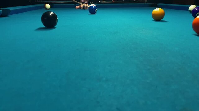 Male hand with billiard cue stick hits white ball on blue pool table