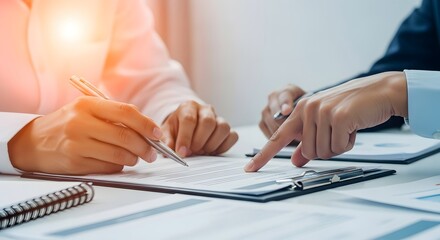 Two people in business attire review and sign documents