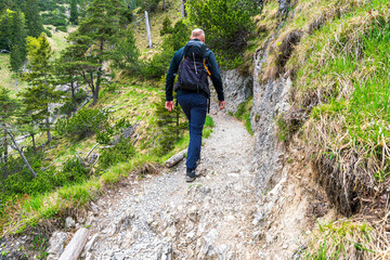 Naklejka premium Happy Man with glasses and a black jacket and backpack along to the Bavarian hiking paths