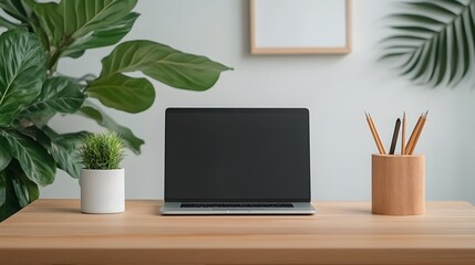 Fototapeta premium Clean minimalist workspace with a laptop on a wooden desk accented by a small plant and a wooden pencil holder