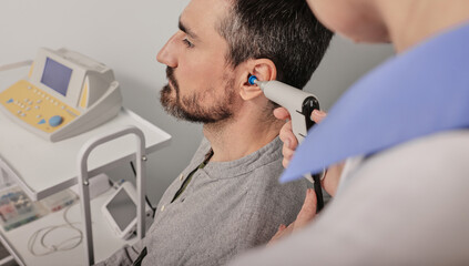 Tympanometry. Doctor audiologist doing tympanometry and test of middle-ear function to mature man...