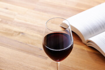 Glass of red wine with open book on table