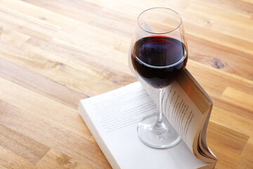 Glass of red wine with open book on table