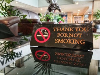 A “Thank You For Not Smoking” sign placed on a glass table in a comfortable and well-organized...