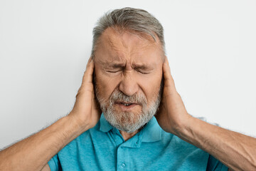 Migraine, headache, stress. Elderly man with headache touching hands on temples with suffering...