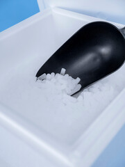 Black plastic scoop containing dry ice pellets in styrofoam cooler container