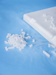 White dry ice pellets pouring from styrofoam container edge