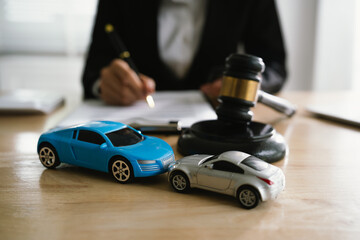 A lawyer uses a gavel near a toy car, symbolizing legal proceedings, car insurance claims, court...