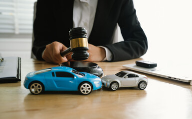 A lawyer uses a gavel near a toy car, symbolizing legal proceedings, car insurance claims, court...