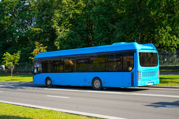 An electric bus travels along a green alley on a city route