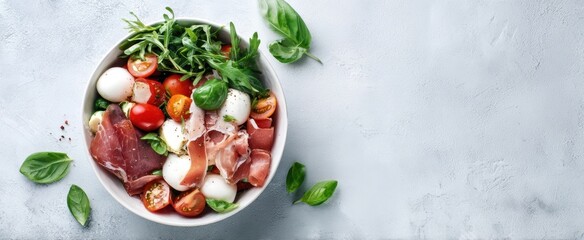 The colorful salad bowl featuring fresh vegetables and prosciutto.