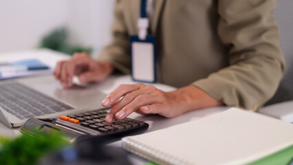 Business professional calculates financial data using calculator and laptop managing expenses budget analysis office desk work tax preparation