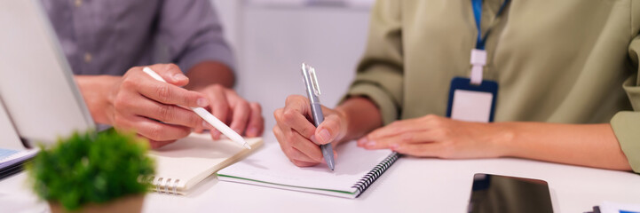 Asian business professionals collaborate taking notes strategizing business growth planning project...