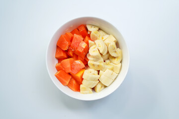Colorful Banana and Papaya Fruits in White Bowl – Fresh and Natural on White Background.