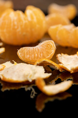 the reflection of an orange citrus tangerine in a black mirror surface, a peeled and juicy tangerine on a black mirror