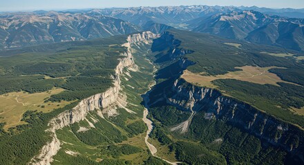 Aerial view of a deep gorge with steep cliffs and lush green forests under a clear blue sky day light